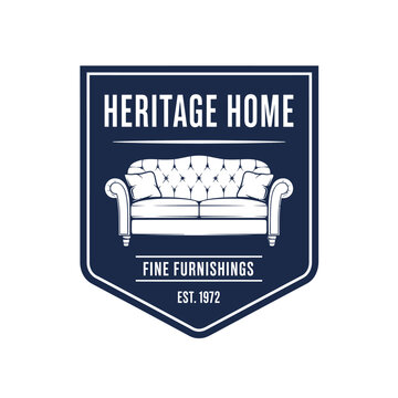A crest-shaped logo in navy blue, white outlines a sofa, with text "Heritage Home, Fine Furnishings, Est. 1972.