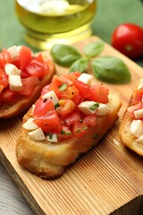 Tasty bruschettas with tomatoes, mozzarella cheese and basil served on wooden table, closeup