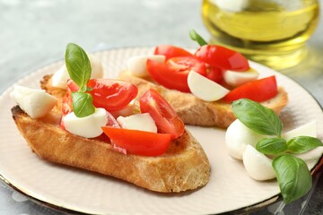 Tasty bruschettas with mozzarella cheese, tomatoes and basil on grey table, closeup