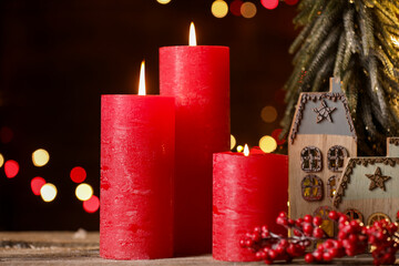 Burning candles and Christmas decor on wooden table against dark background with blurred lights, closeup. Bokeh effect