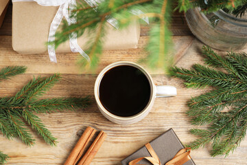 Aromatic coffee in cup, gift boxes and fir tree branches on wooden table, flat lay. Christmas...