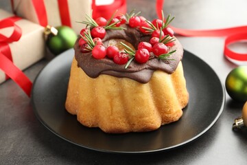 Tasty cake with cranberries, gifts and Christmas decor on grey table, closeup