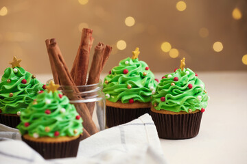 Christmas tree shaped cupcakes and cinnamon on white table, closeup
