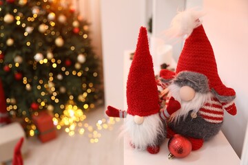 Fototapeta premium Funny Christmas gnomes on dresser in decorated room, closeup. Space for text