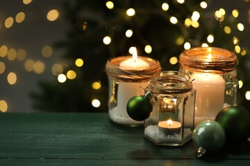 Beautiful Christmas lanterns and festive decor on green wooden table against blurred lights, space for text. Bokeh effect