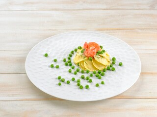 A beautifully presented dish features stuffed ravioli topped with succulent shrimp and vibrant green peas. This culinary delight is perfect for a sophisticated dining experience