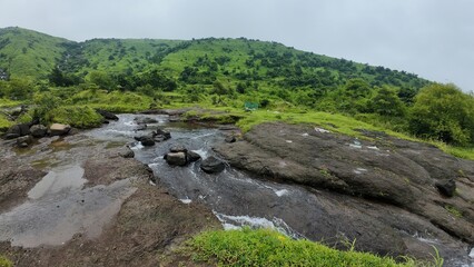 Monsoon Stream Flowing Over Rocky Terrain, Surrounded by Lush Green Vegetation