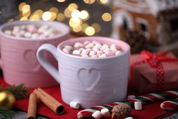 Tasty cocoa with marshmallows, cinnamon and Christmas decor on grey table against blurred lights, closeup