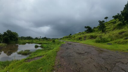 Lush Green Western Ghats Landscape: A Dirt Road Winding Through Rain-Soaked Hills and Dense Vegetation Under a Moody, Overcast Sky