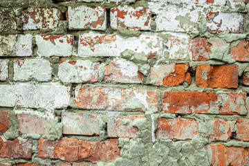 A dilapidated old red brick wall painted white as an abstract background.