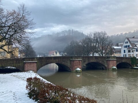 Historische Steinbr&uuml;cke &uuml;ber den winterlichen Neckar in Sulz am Neckar mit Nebel &uuml;ber den H&uuml;geln und ruhiger Kleinstadtatmosph&auml;re