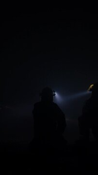 Rescue forces search for survivors inside a dark tunnel using flashlights