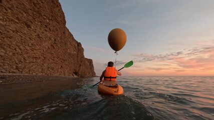 Kayak paddling sea man exploring rugged cliff coastline at serene sunset creating an adventurous waterscape