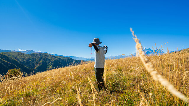 Hiker stretching in tall grass with stunning mountain view near Mestia, Svaneti, Georgia. Active outdoor lifestyle and nature freedom. - Powered by Adobe