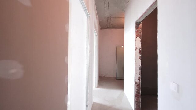 Raw, unfinished room with concrete ceiling and drywall walls. Sunlight streams through a large window, illuminating the space ready for renovation