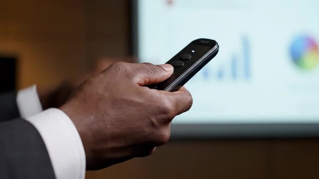 Male hand operating presentation remote control during data display