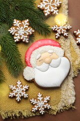 Tasty gingerbread cookies and fir tree branches on brown background, flat lay. Christmas treat