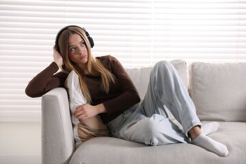 Obraz premium Depressed teenage girl in headphones on sofa at home