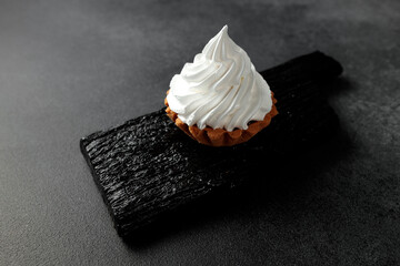 A sand basket with protein cream stands on a black wooden board on a gray background