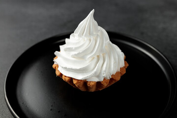 cake basket with protein cream in a black round plate on a black background