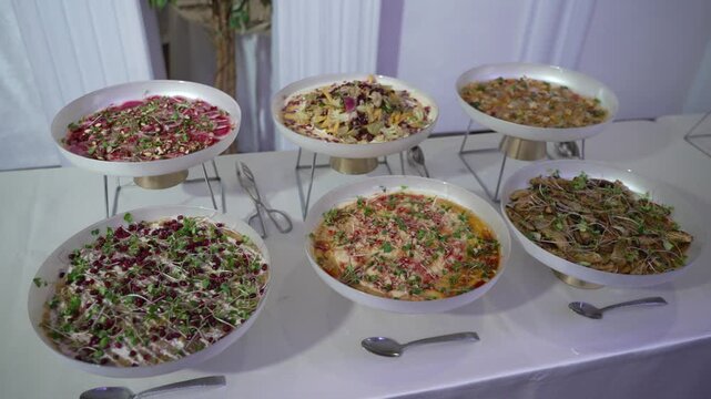 An assortment of fresh, gourmet salads beautifully presented on a buffet table. This elegant display evokes a sense of healthy, upscale dining, perfect for catering or event promotions.