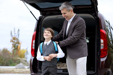 Father taking his son to school near car outdoors