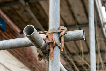 two steel scaffolding pipes cross each other and are secured with anchors