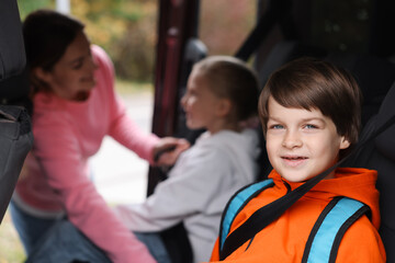 Mother taking her children to school by car, selective focus