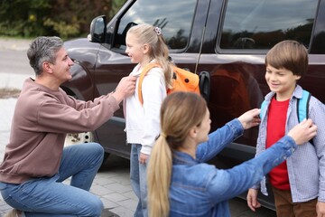 Parents taking their children to school near car outdoors