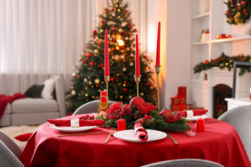 Stylish Christmas table setting with plates, festive decor and candles indoors