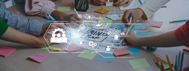 A dynamic scene showing a group engaged in mind mapping using colorful sticky notes and digital...