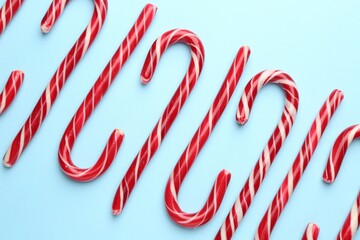 Tasty candy canes on light blue background, flat lay. Merry Christmas and Happy New Year