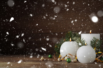 Fototapeta premium Christmas composition with burning candles on table under falling snow. Greeting card