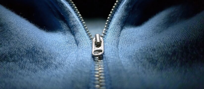 Close-up of a blue zipper on a fuzzy fabric.