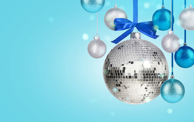 Obraz premium Merry Christmas and Happy Holidays greeting card. Shiny disco ball and festive ornaments on light blue background, bokeh lights. Banner design with space for text