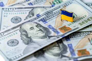Hundred dollar bills are scattered on the table. National flag of Ukraine on the dollars. Finance of the United States in Ukraine.