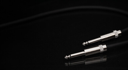 Two silver TRS connectors for the analog audio signal are placed against a black background. Professional jack connectors for sound equipment. Audiophile technologies concept.