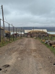 Obraz premium Rural Dirt Road and Old Stone Houses in Cloudy Georgian Village