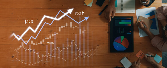 Team members collaborate on financial analysis, surrounded by charts and graphs, highlighting successful trends and performance metrics on a wooden table. Scalp