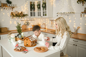A mother and son are preparing a gingerbread house for the Christmas and New Year holidays.
