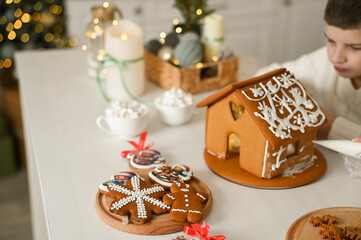 A mother and son are preparing a gingerbread house for the Christmas and New Year holidays.