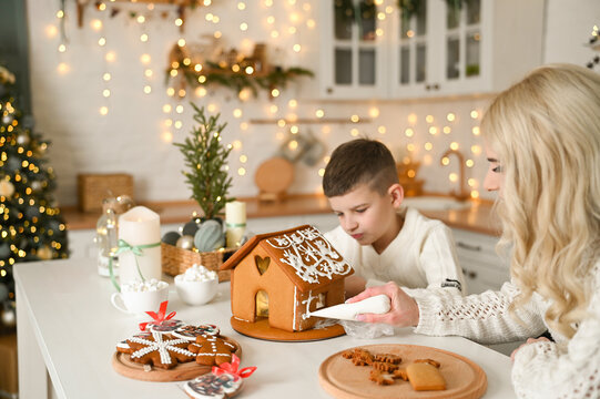 A mother and son are preparing a gingerbread house for the Christmas and New Year holidays.