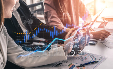 A business team collaborates in a modern office, engaging with financial data and technology. They analyze graphs and charts on devices, promoting teamwork and insight. Scalp