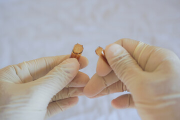 A medic in gloves breaks off the edge of a glass ampoule.