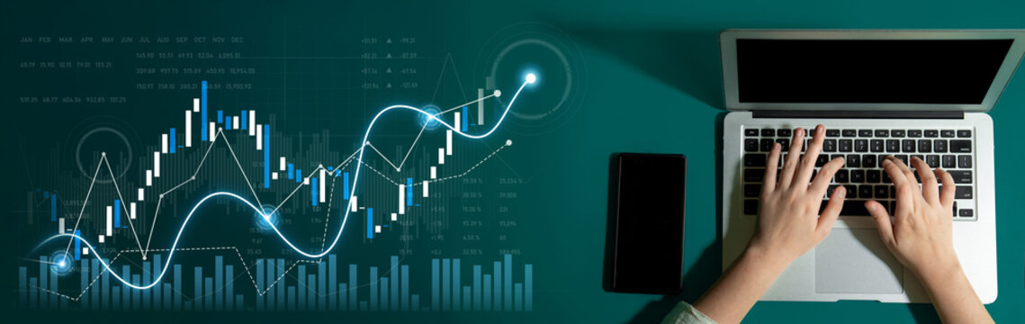A modern workspace featuring hands typing on a laptop with stock market graphics, highlighting data analysis and financial growth in a digital setting. Scalp - Powered by Adobe