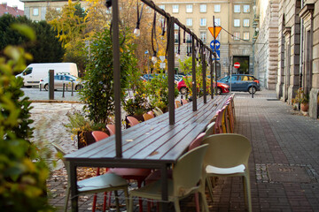 Outdoor dining area with colorful chairs on a quiet city street in autumn