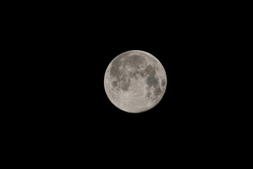 Full moon in the night sky. Moon Closeup Showing the Details of Lunar Surface in Black Background