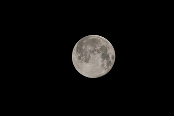 Full moon in the night sky. Moon Closeup Showing the Details of Lunar Surface in Black Background