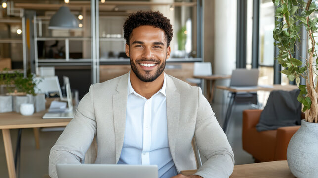 Smiling businessman in blazer at modern office desk, confident and approachable professional