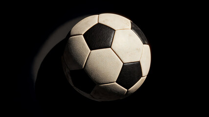 Fototapeta premium A Worn Classic Soccer Ball Illuminated by a Dramatic Spotlight, Floating in Darkness.
